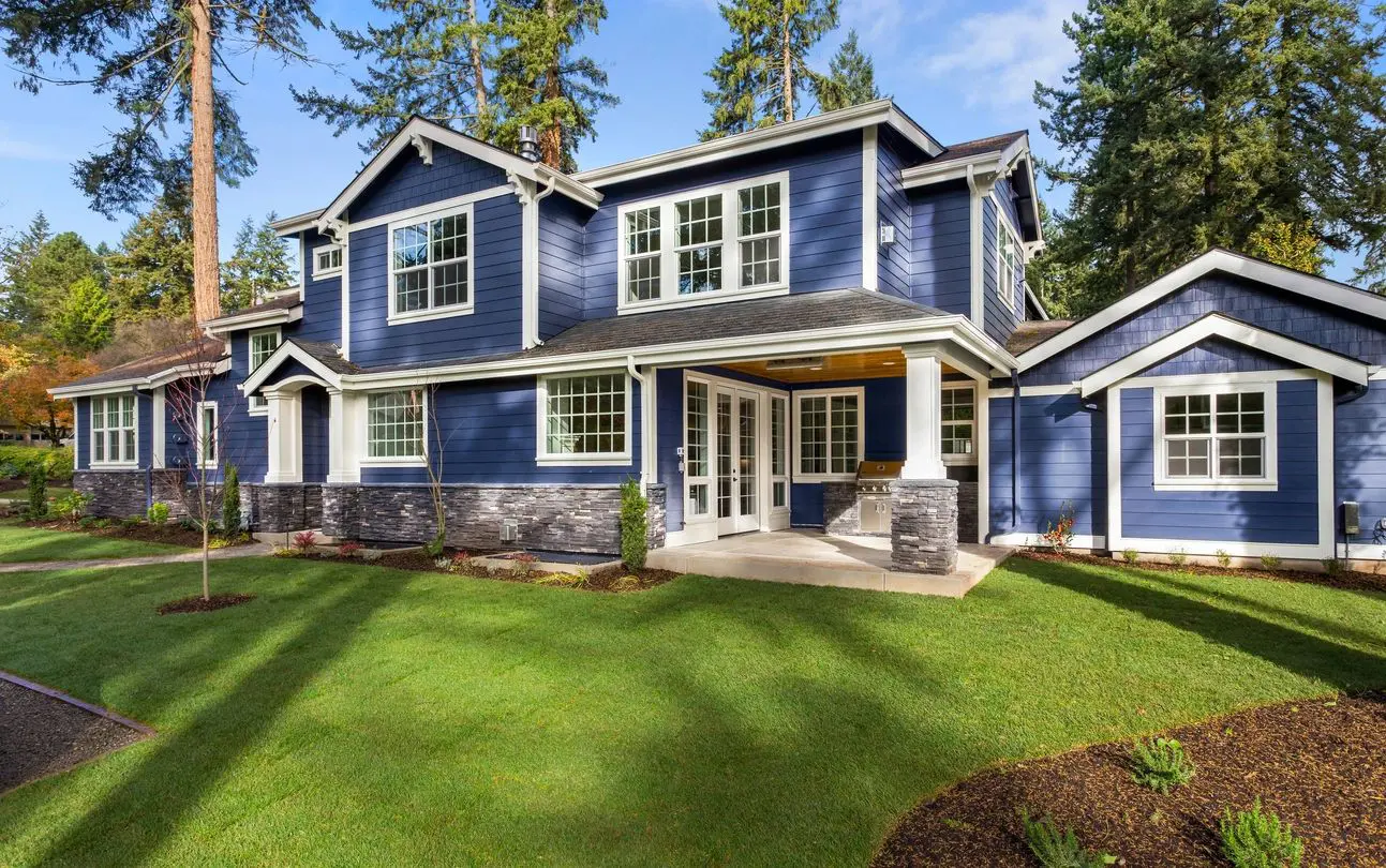 A blue house with white trim and green grass.